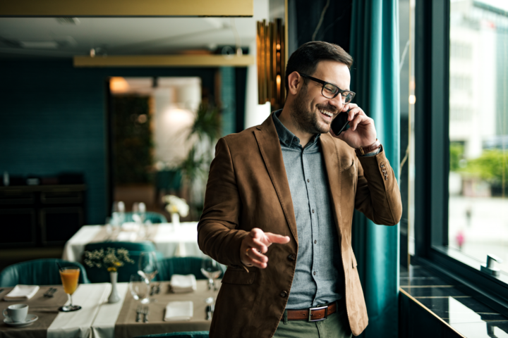Portrait of a smiling businessman in restaurant talking on smart phone.